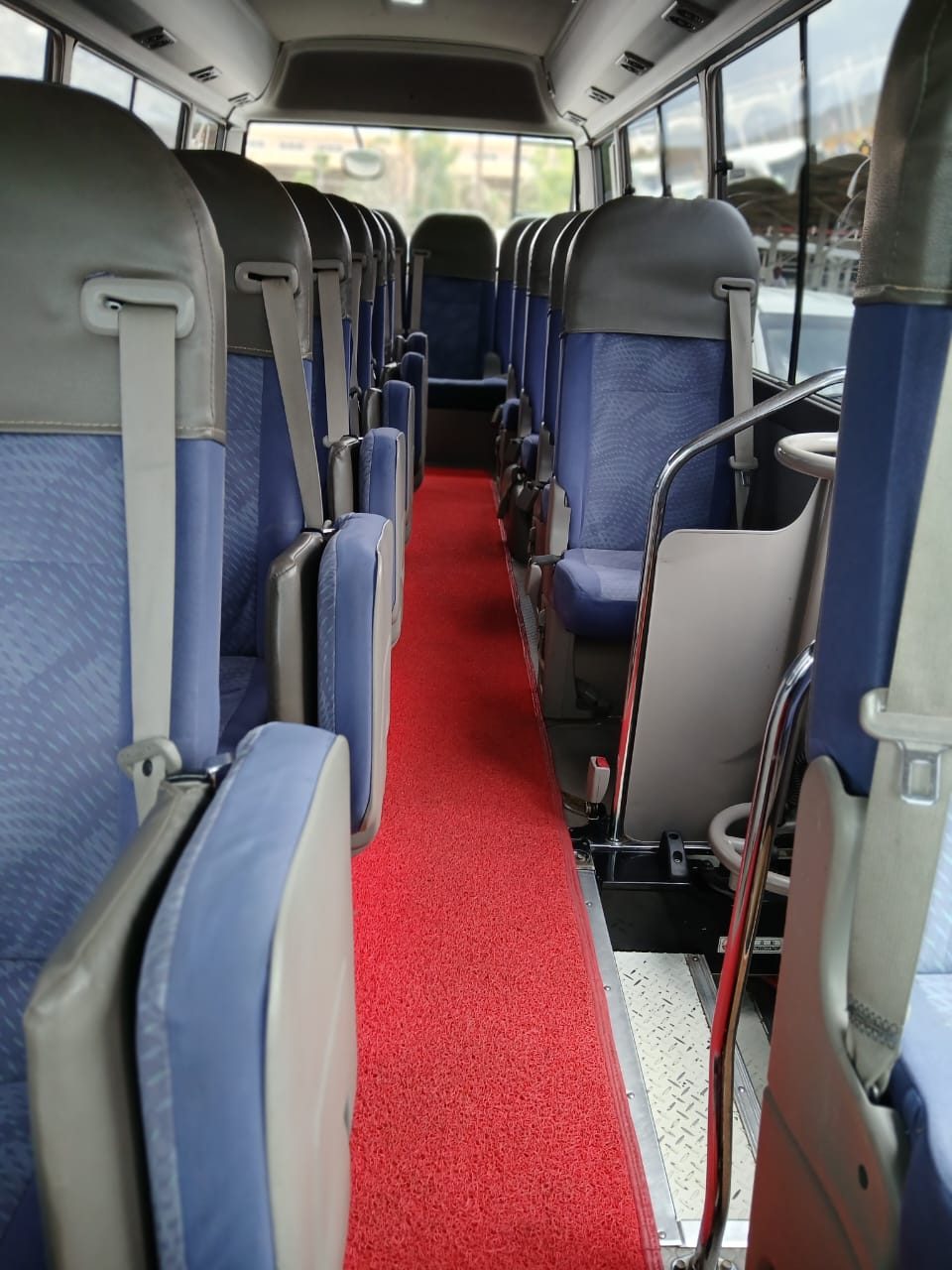 Interior aisle of the Coaster bus with reclining seats and seat belts