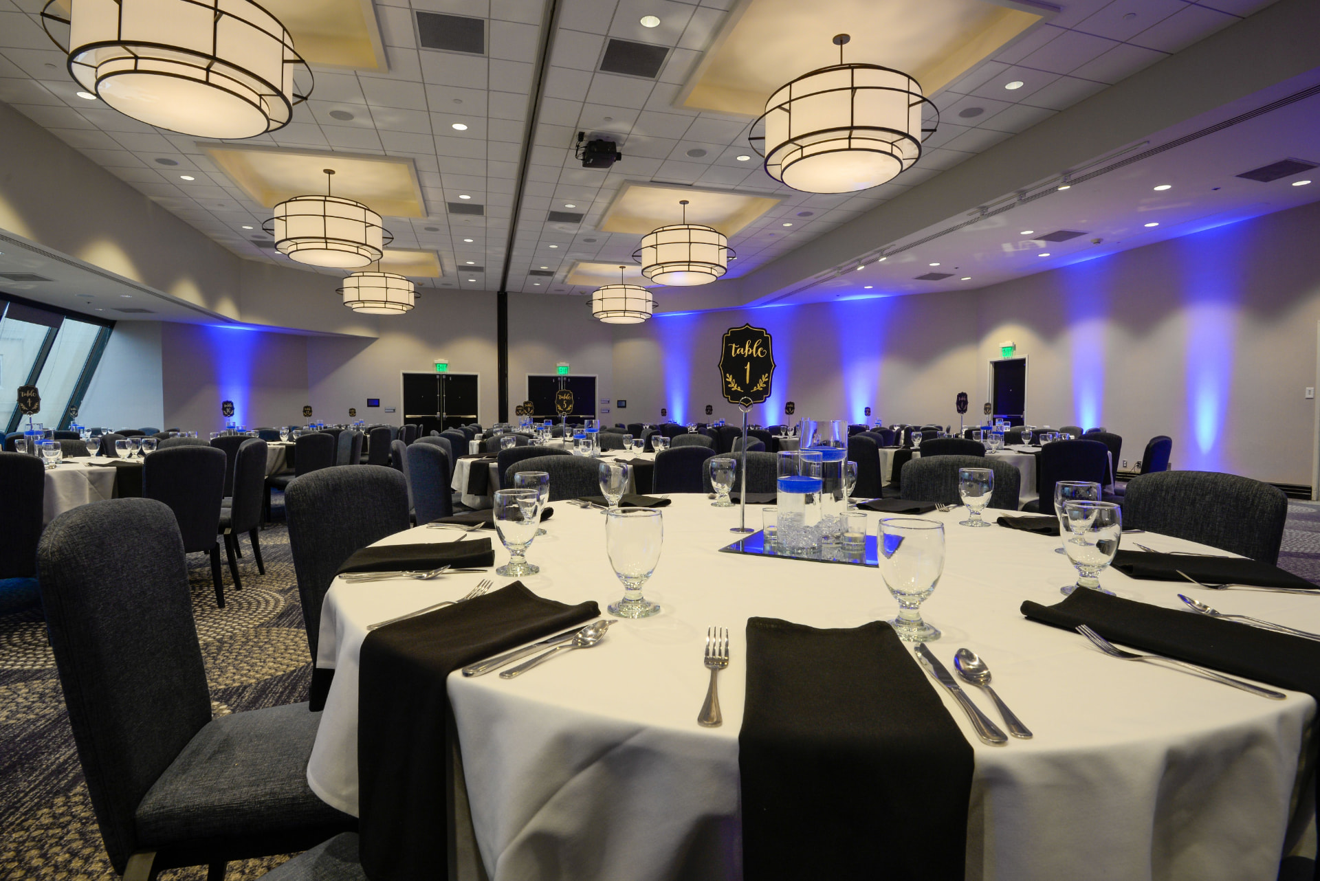 Ballroom set with round tables, uplighting and table numbers